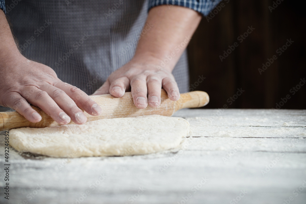  hands cooking dough on dark wooden background