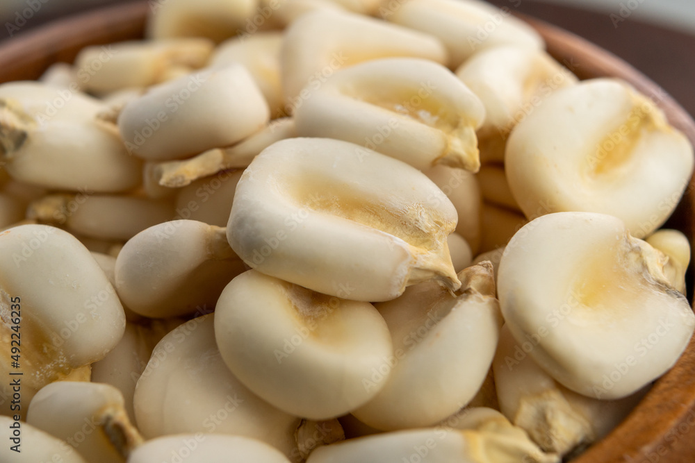 Whole dried hominy. Dry maize mote grain in wooden bowl