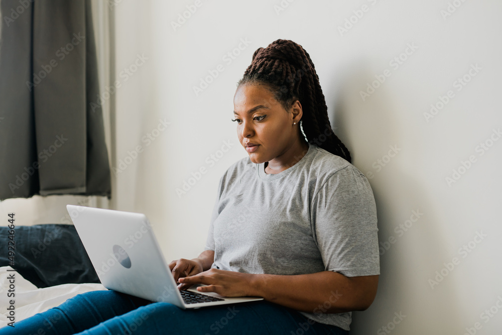 African american young woman using laptop on bed - technologies and communication and social network concept African american young woman using laptop on bed - technologies and communication and social network concept