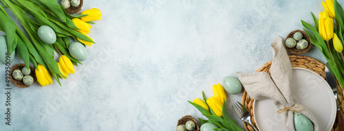 Photography Easter festive table setting with easter eggs decoration and yellow tulips flowers on gray background