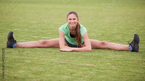 This is flexibility. Shot of a young woman stretching on a grassy field.