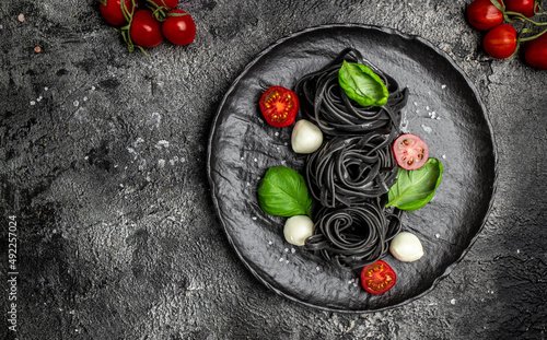 black pasta with cuttlefish ink and green basil leaves. Pasta of durum wheat semolina with squid ink. Vegan or gluten free diet. Restaurant menu, dieting, cookbook recipe top view