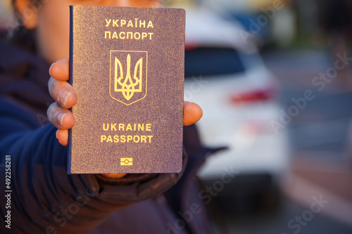 Hands holding Ukrainian biometric passport on a car background