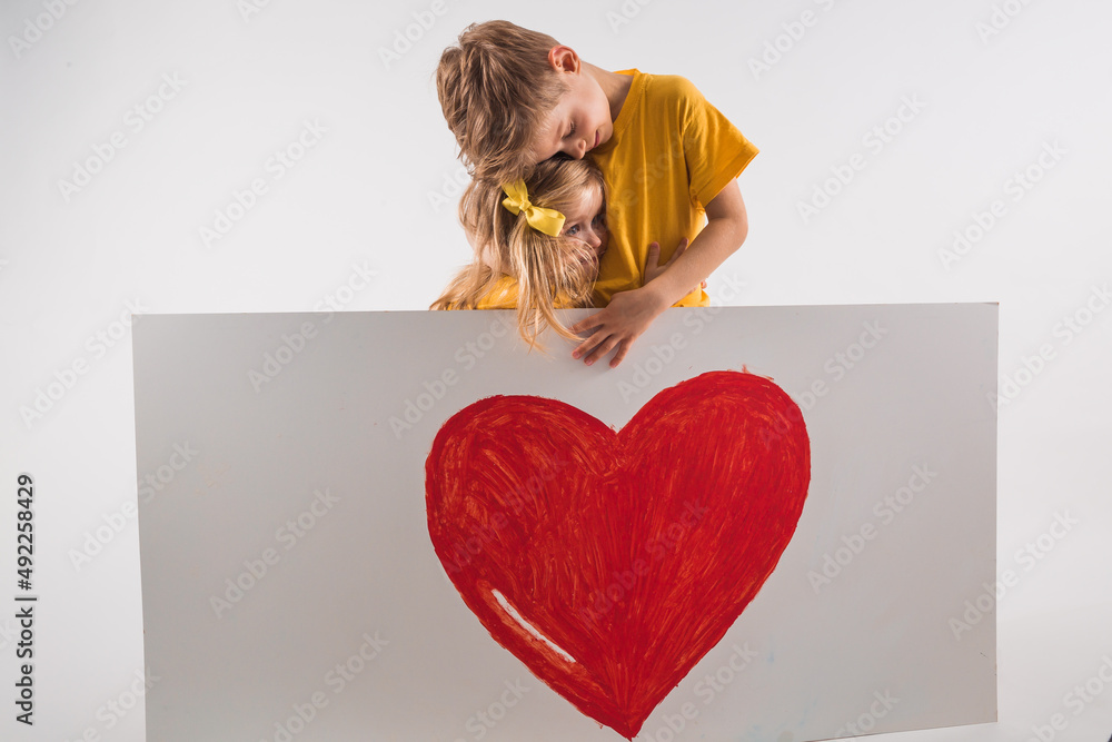 happy Boy and Girl are holding white board with a big heart on white ...