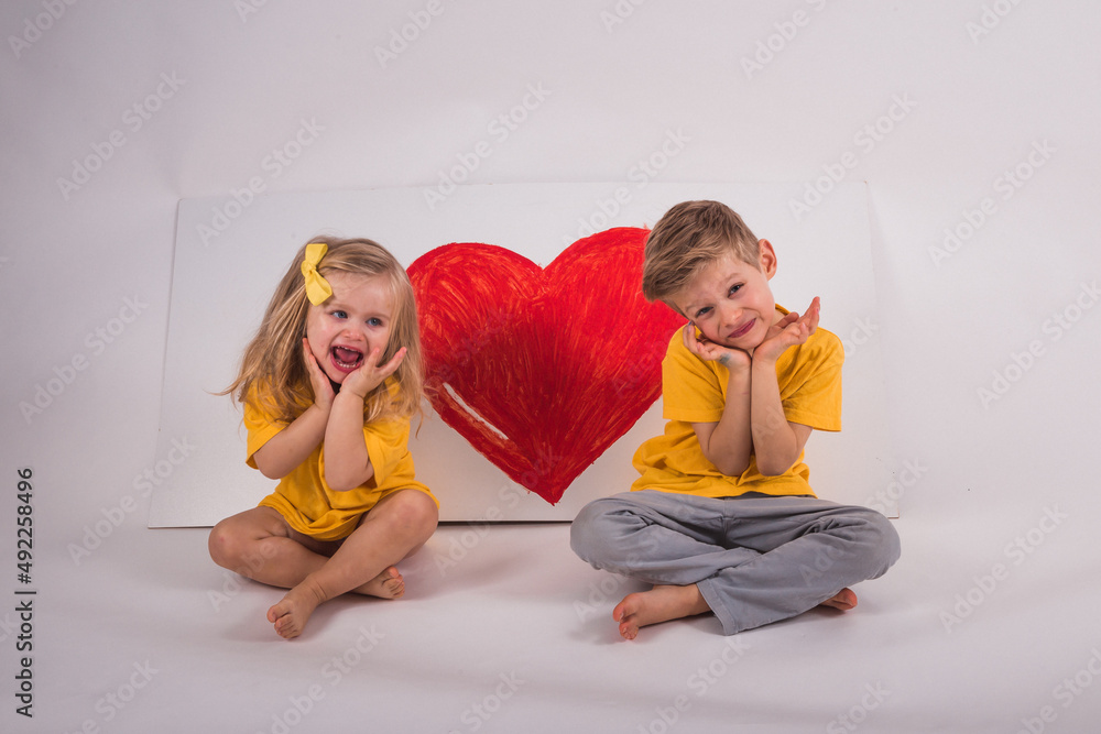The happy boy and girl is sitting on the floor. Next to them is a big ...