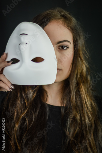 Being authentic and true concept - Portrait of a beautiful young woman with long hair taking off her mask