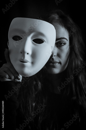 Be authentic and true concept - Black and white portrait of a beautiful young woman with long hair taking off her mask