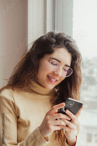 Close-up of a woman smiling while using her mobile. Technology concept.