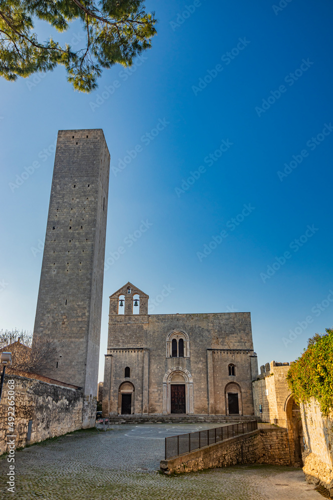 The village of Tarquinia, Viterbo, Lazio, Italy - The tower and facade of the Church of Santa Maria in Castello, in Romanesque style. Three arched doors, the mullioned window and the bell tower.