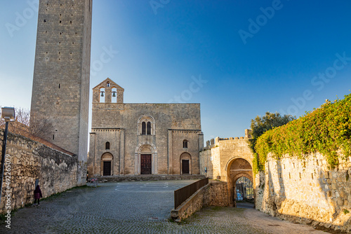 The village of Tarquinia, Viterbo, Lazio, Italy - The tower and facade of the Church of Santa Maria in Castello, in Romanesque style. Three arched doors, the mullioned window and the bell tower. photo