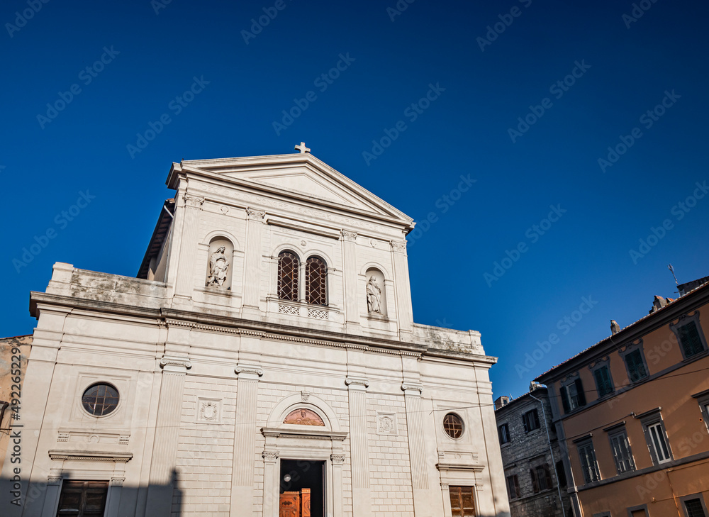 The village of Tarquinia, Viterbo, Lazio, Italy - The facade of the church of Saints Margherita and Martino. The mullioned window in the center and the two niches with the statues of the saints.