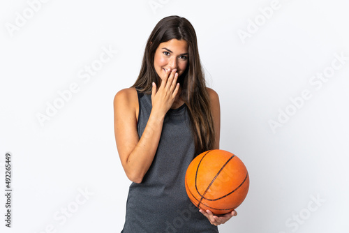 Young brazilian woman playing basketball isolated on white background happy and smiling covering mouth with hand © luismolinero