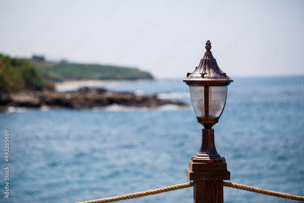 Glass lantern on the pier on the mediterranean sea. Seaside lighting