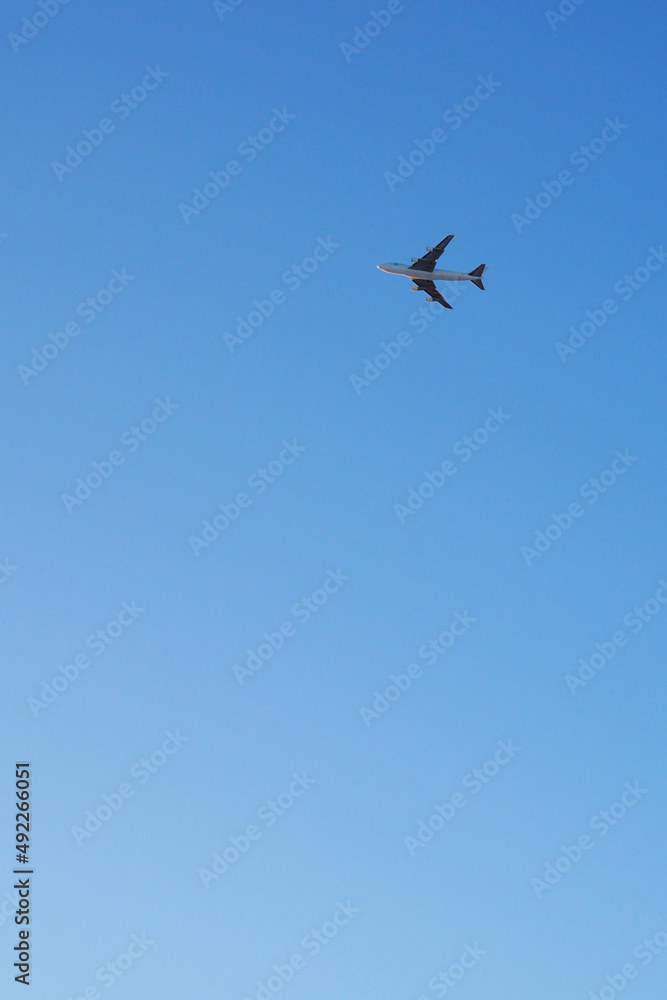 The big four-engine transport airplane is flying far away in the blue sky. Vertical illustration about international air freight The big four-engine transport airplane is flying far away in the blue sky. Vertical illustration about international air freight