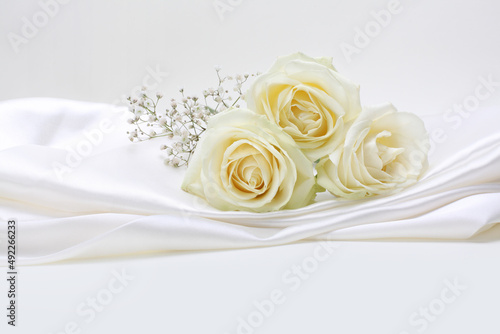Beige rose flower bouquet on white silk copy space background.