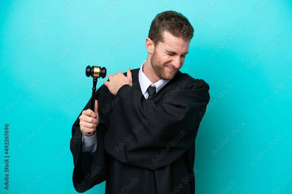 Judge caucasian man isolated on blue background suffering from pain in shoulder for having made an effort Judge caucasian man isolated on blue background suffering from pain in shoulder for having made an effort