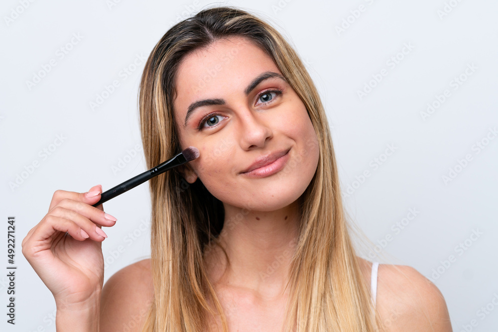 Young caucasian woman isolated on white background holding makeup brush