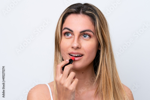 Young caucasian woman isolated on white background holding red lipstick