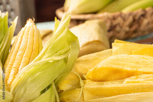 Brazilian corn snack pamonha and cornflower arranged on a table with green and white tablecloth, selective focus. photo