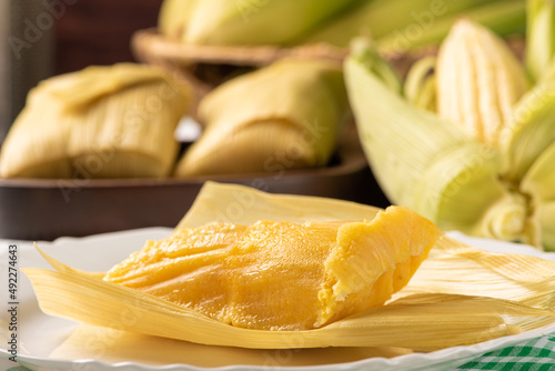 Brazilian corn snack pamonha and cornflower arranged on a table with green and white tablecloth, selective focus.