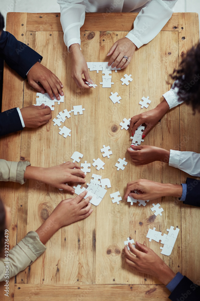 The bigger picture can only be seen with everyones effort. High angle shot of a group of unrecognisable businesspeople building a puzzle together. The bigger picture can only be seen with everyones effort. High angle shot of a group of unrecognisable businesspeople building a puzzle together.