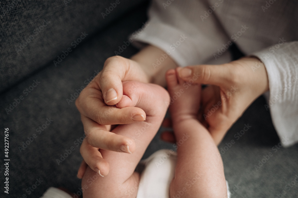 om holds the baby's legs in her hands, warm affection and care