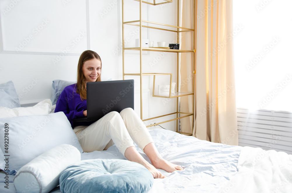 the girl lies in bed and works on a laptop. the concept of homeschooling and online work. blogging the girl lies in bed and works on a laptop. the concept of homeschooling and online work. blogging
