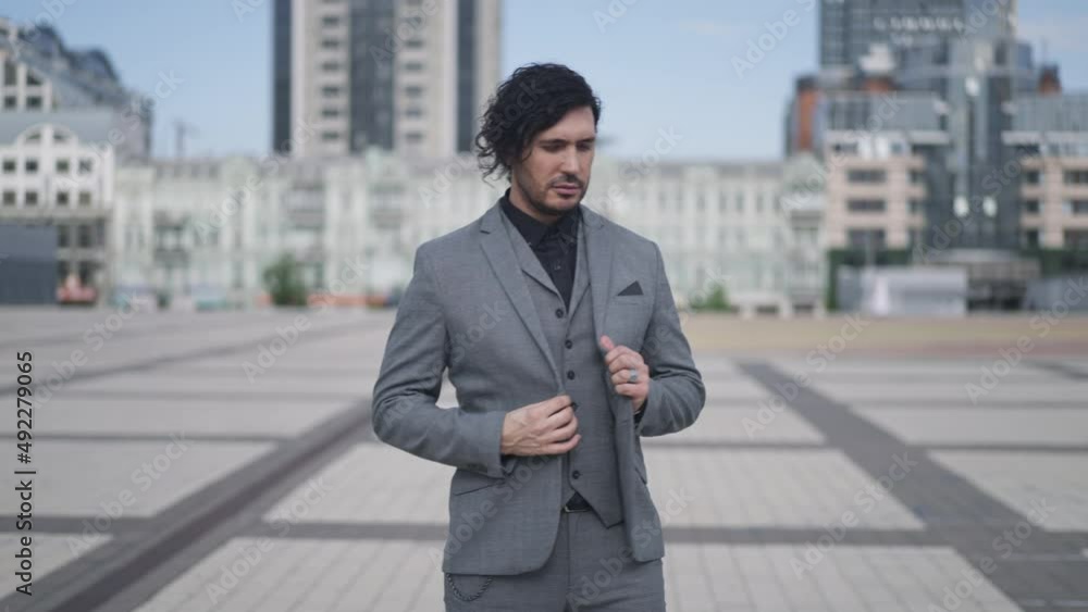 Elegant man standing on city square waiting for meeting outdoors. Positive Caucasian businessman and businesswoman shaking hands in slow motion greeting talking and smiling Elegant man standing on city square waiting for meeting outdoors. Positive Caucasian businessman and businesswoman shaking hands in slow motion greeting talking and smiling