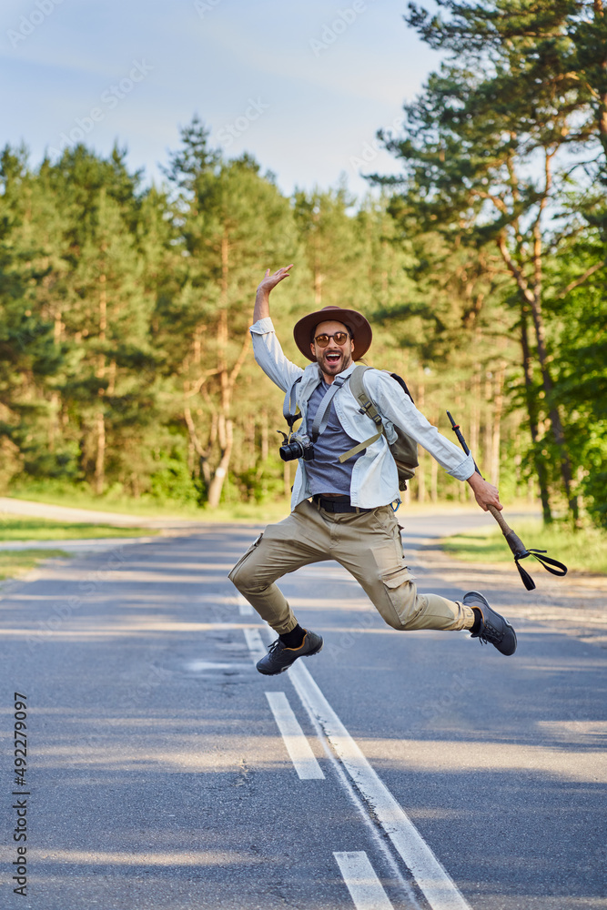 Young man jumping on rural road enjoying summertime freedom