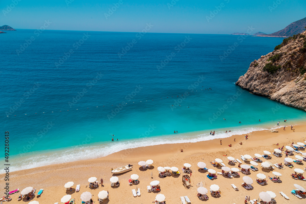 Aerial View From Flying Drone Of People Crowd Relaxing On Beach. Swimming people in sea. Top view of Kaputas Beach between Kas and Kalkan Aerial View From Flying Drone Of People Crowd Relaxing On Beach. Swimming people in sea. Top view of Kaputas Beach between Kas and Kalkan