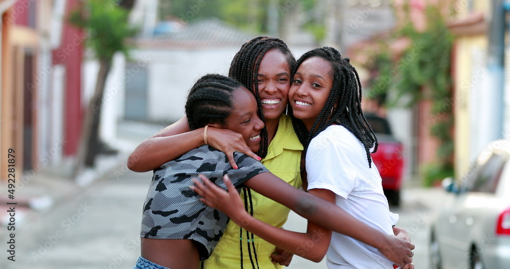 Loving mother and teen daughters embrace. MIxed race teenage girls hugging mom