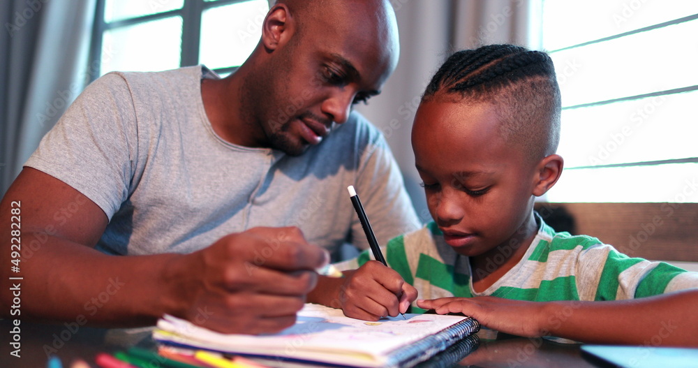 Naklejka premium Little boy studying at home doing homework with father help