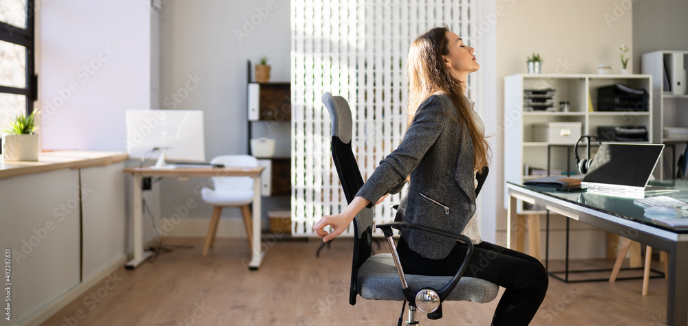 Employee Stretching At Office Desk Employee Stretching At Office Desk
