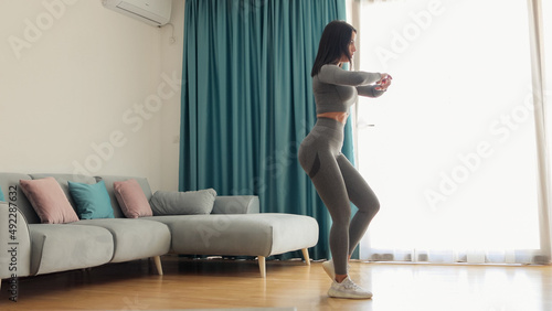 Young sporty woman doing squat morning exercise. home fitness routine. Woman with strong glutes workout at home. Female gymnastics. Butt workout motivation. photo