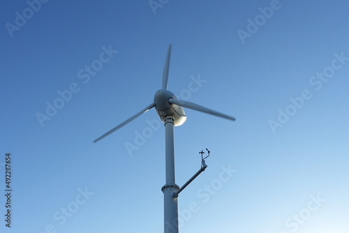 青空と下から見上げた1基のプロペラ型の風力発電機