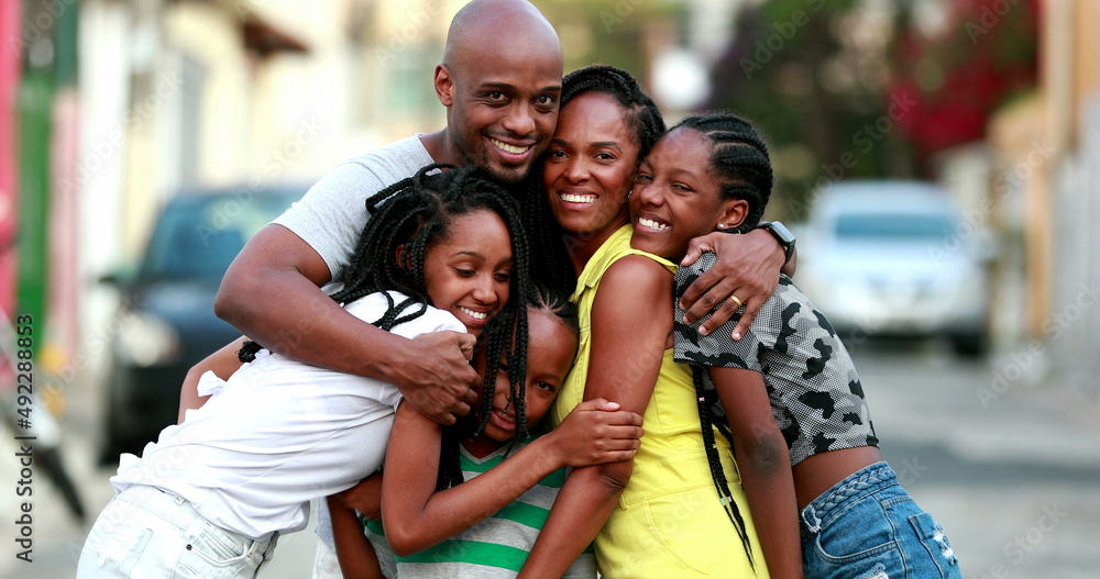 Fototapeta premium Beautiful black family embrace. Loving father hugging wife and children. African ethnicity