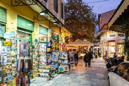 A narrow street of gift and souvenir shops and cafes in the colorful illuminated Plaka district at night in Athens  Greece.