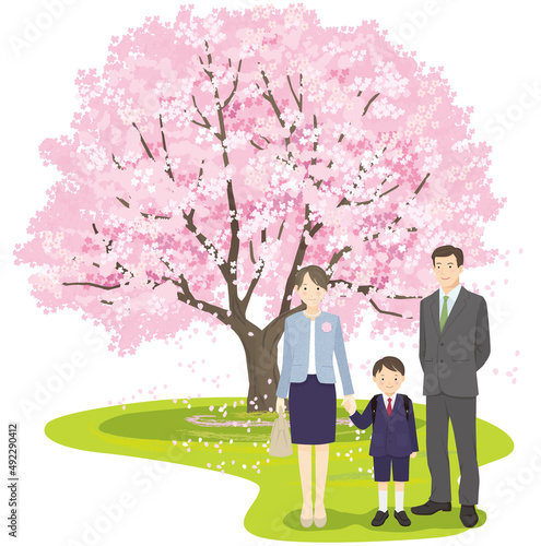 桜の木の前で並んで立つ新入生の男の子と両親