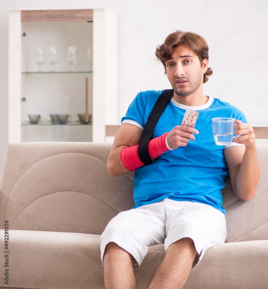 Young man with injured arm sitting on the sofa Young man with injured arm sitting on the sofa