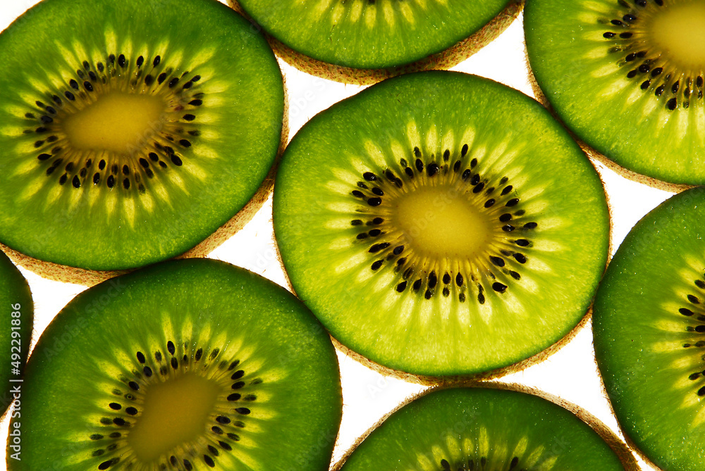 kiwi slice against light, closeup view, green color fruit on white background with space for text