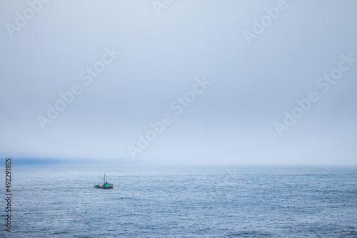 A fishing boat in the fog just off the coast of Cape Flattery, Washington photo