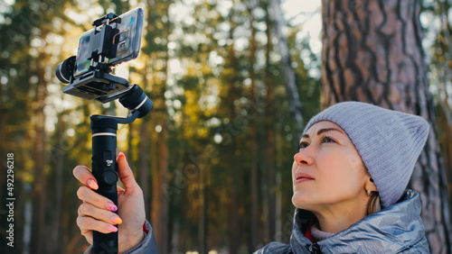 Woman Holding On Handheld Film 3-axis Gimbal Stabilization Device in Winter for Smartphone. Girl Blogger Make Selfie, Broadcast Video Blogging, Vlogging. Videographer Operator Take Photo Video.