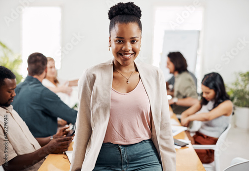 I stand here as a confident go-getter. Portrait of a young businesswoman standing in an office with her colleagues in the background. © Mikolette M/peopleimages.com