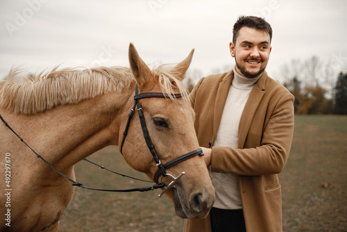 Handsome brunette man and a brown horse in the field