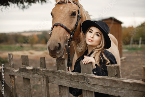Woman touching a brown horse behinde the fence on a farm photo