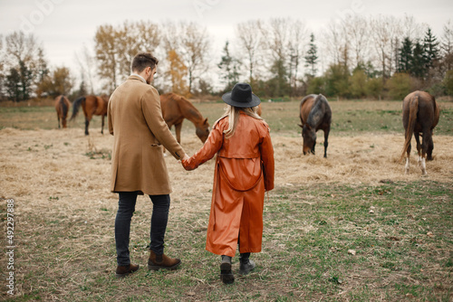Romantic couple walking in the field with horses