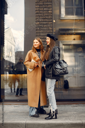 Two female friends in fashion clothes standing on the street