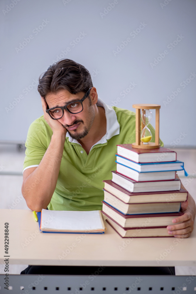 Young male student in time management concept Young male student in time management concept