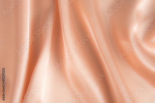 Abstract light brown silk fabric texture background. Creases of satin