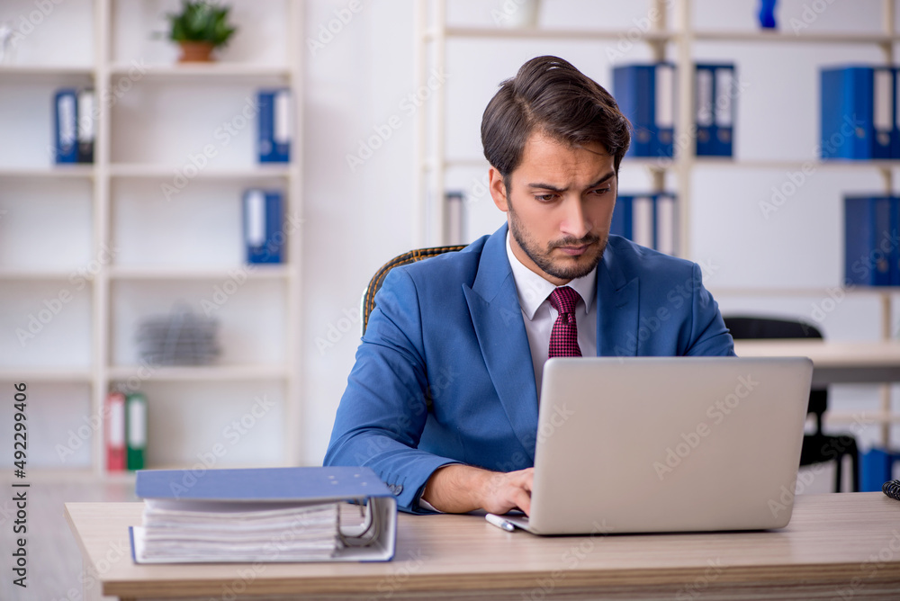 Young male employee and too much work in the office Young male employee and too much work in the office